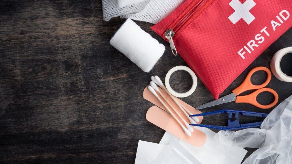 Contents of a red first aid kit laid out on a table, showing medical supplies like bandages, scissors, and gloves — ideal visual for a first aid kit update reminder.