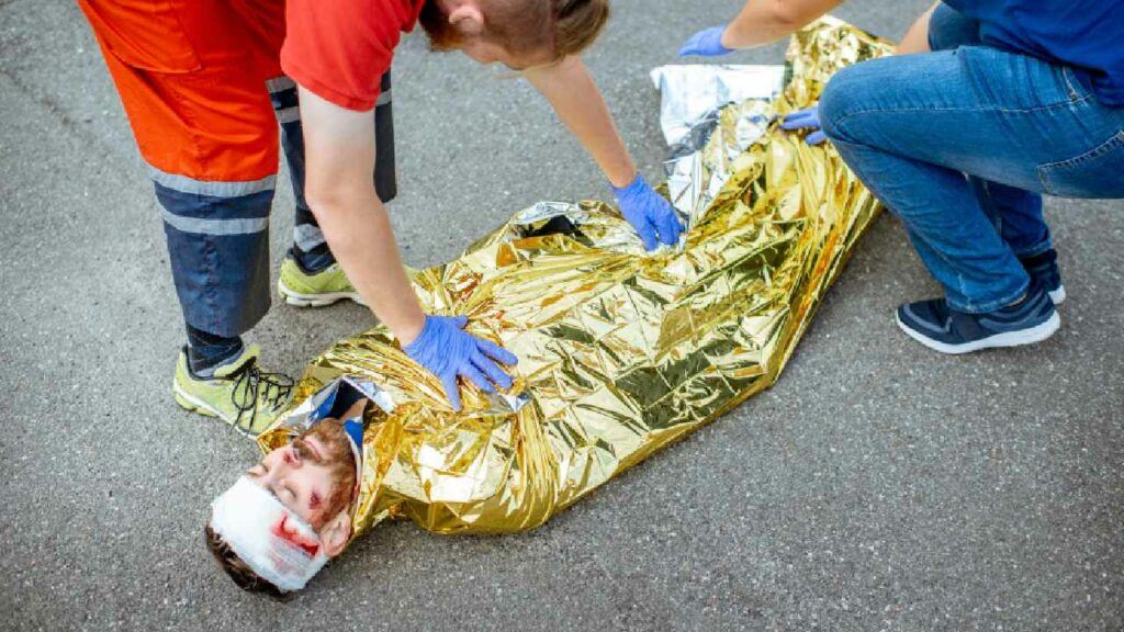 Man who has had an accident in thermal blanket given first aid for shock